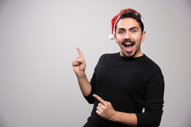 Homem sorridente com chapéu de Papai Noel aparecendo os dedos.