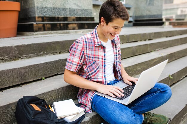 Homem sorridente com laptop a estudar