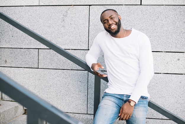 Homem sorridente com smartphone na escada