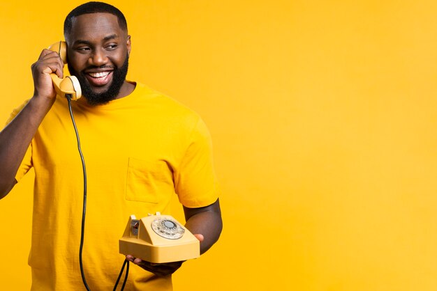Homem sorridente com telefone antigo