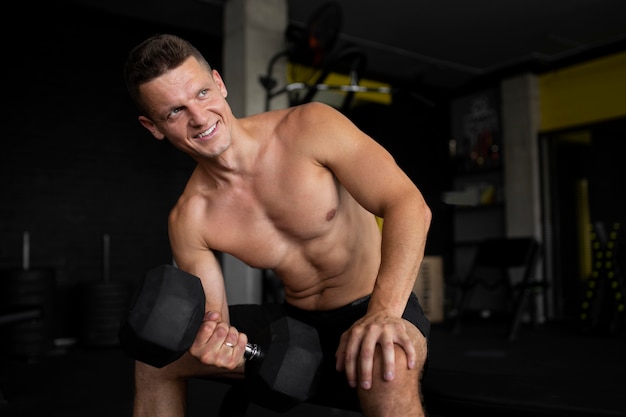 Foto grátis homem sorridente com tiro médio segurando halteres