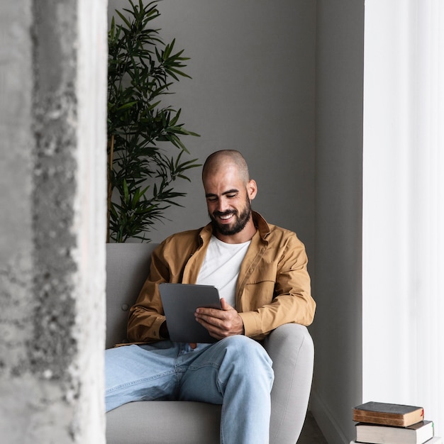 Homem sorridente com tiro médio segurando tablet