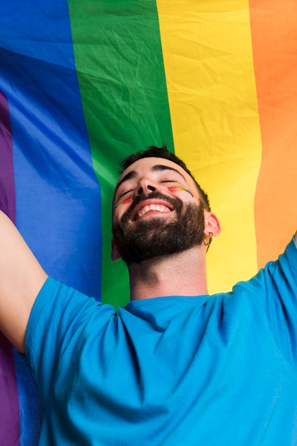 Homem sorridente contra a bandeira lgbt