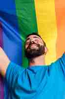 Foto grátis homem sorridente contra a bandeira lgbt