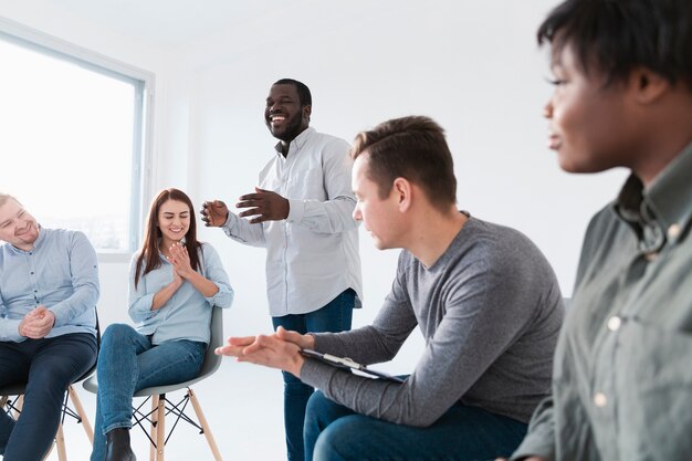 Homem sorridente, conversando com pacientes de reabilitação