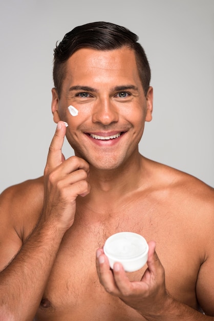 Foto grátis homem sorridente de close-up segurando creme facial