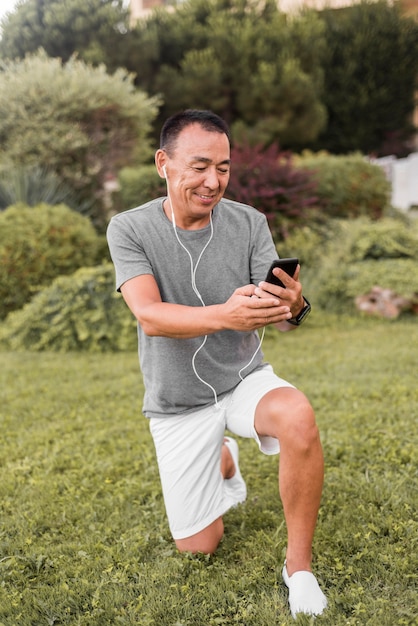 Homem sorridente de foto completa segurando um smartphone