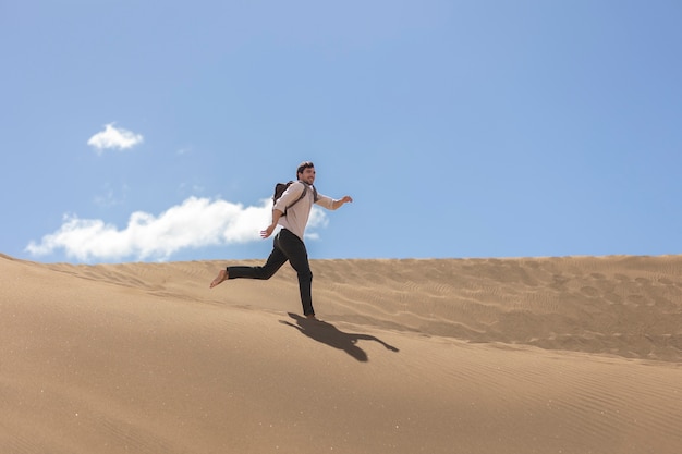 Homem sorridente de tiro completo correndo no deserto