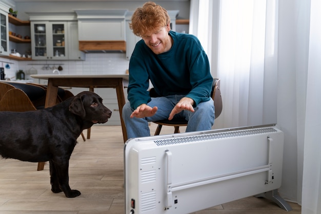 Foto grátis homem sorridente de tiro completo e cachorro em casa