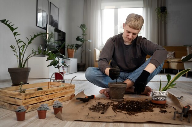 Homem sorridente de tiro completo jardinagem em casa
