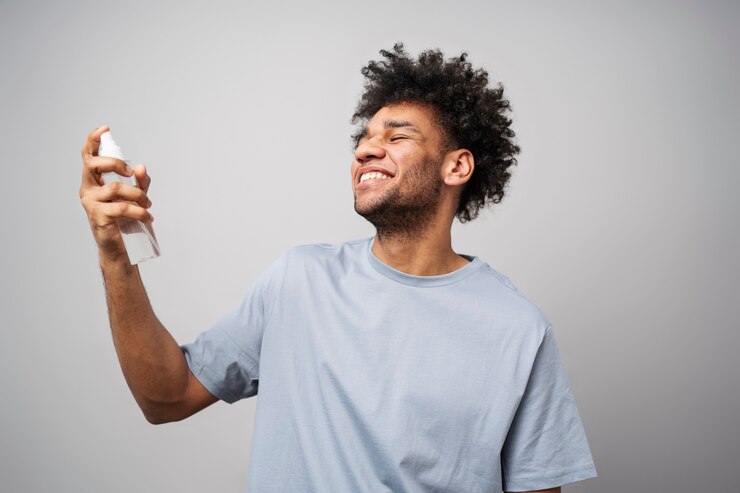 Foto grátis homem sorridente de tiro médio aplicando spray