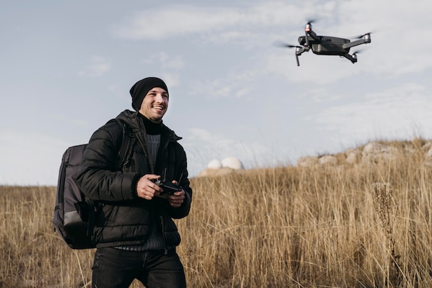 Foto grátis homem sorridente de tiro médio controlando drone