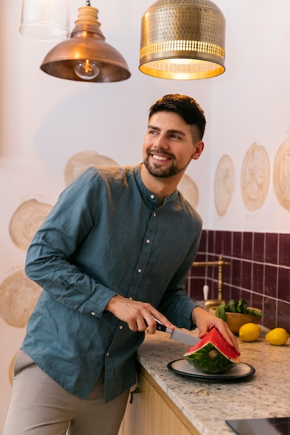 Foto grátis homem sorridente de tiro médio cortando melancia