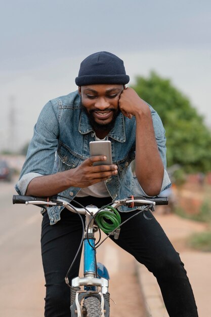 Homem sorridente de tiro médio em bicicleta com telefone