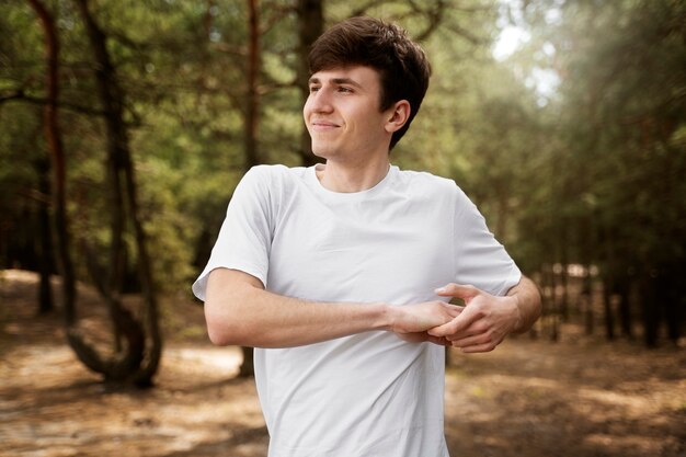 Homem sorridente de tiro médio, estendendo-se na natureza