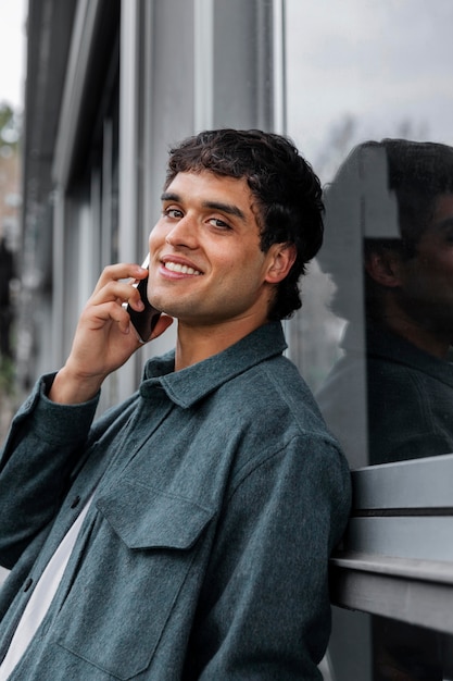 Homem sorridente de tiro médio falando ao telefone