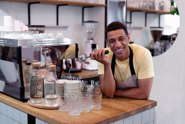 Homem sorridente de tiro médio fazendo café