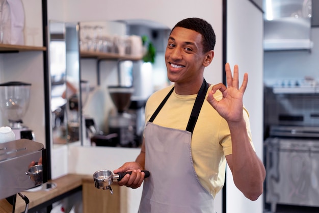 Homem sorridente de tiro médio fazendo café