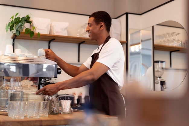 Homem sorridente de tiro médio fazendo café