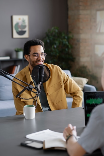 Homem sorridente de tiro médio no podcast