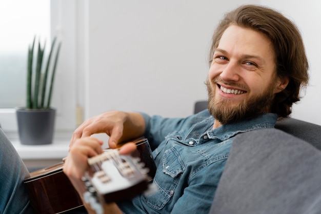 Homem sorridente de tiro médio no sofá