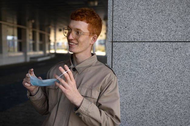 Foto grátis homem sorridente de tiro médio segurando a máscara