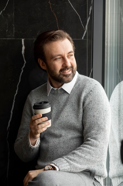 Foto grátis homem sorridente de tiro médio segurando a xícara de café