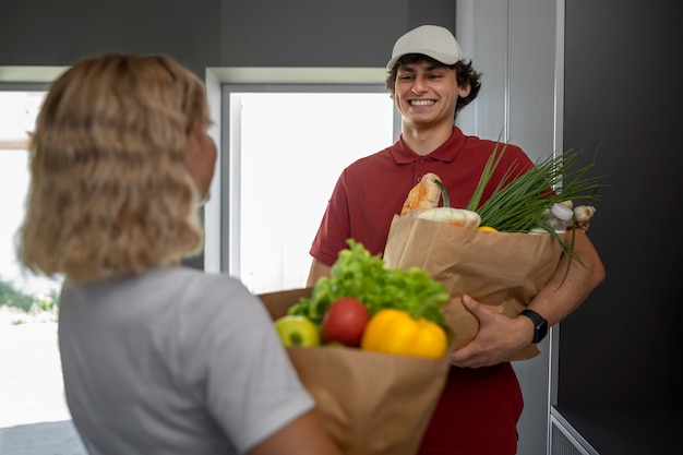 Foto grátis homem sorridente de tiro médio segurando mantimentos