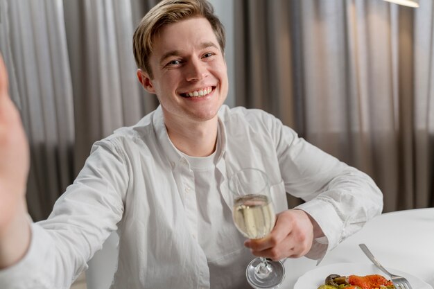 Homem sorridente de tiro médio segurando o copo de vinho