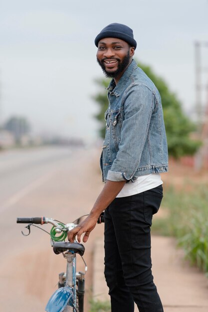 Homem sorridente de tiro médio segurando uma bicicleta