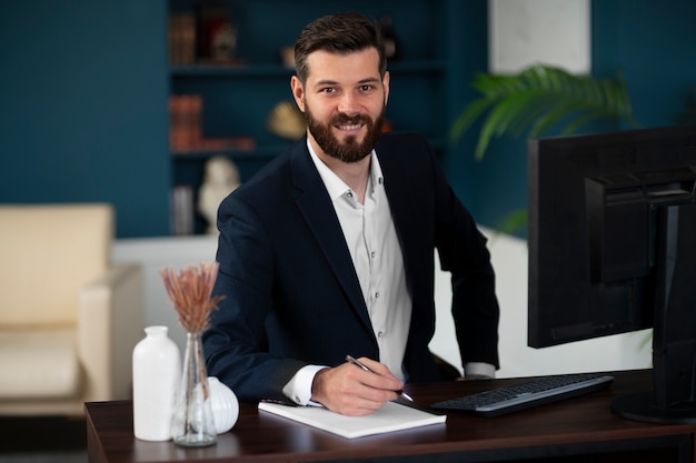 Foto grátis homem sorridente de tiro médio sentado à mesa