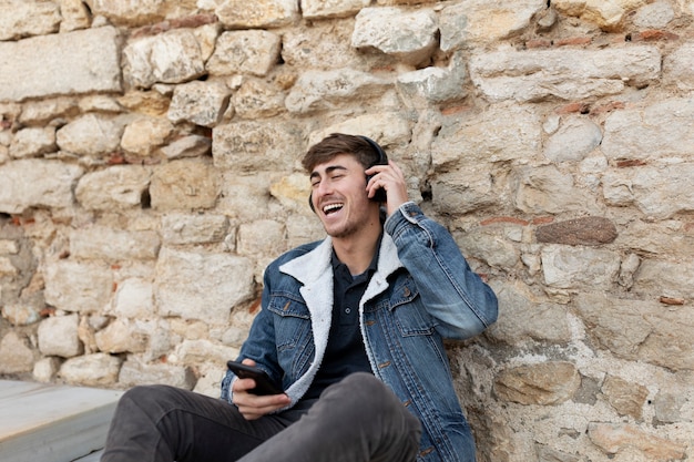 Homem sorridente de tiro médio usando fones de ouvido