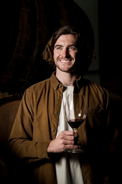 Homem sorridente de vista frontal com copo de vinho