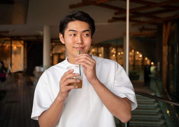 Homem sorridente de vista frontal segurando café gelado