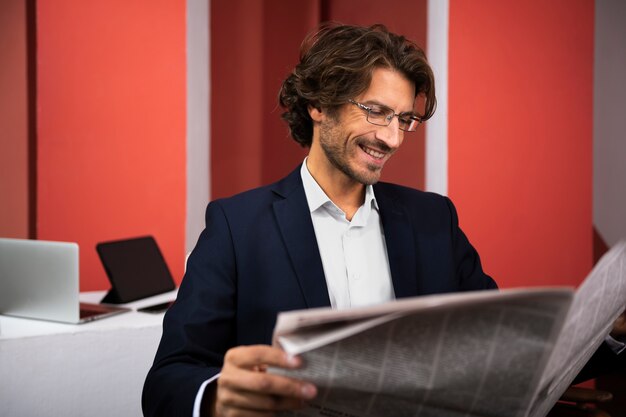 Homem sorridente de vista lateral lendo jornal