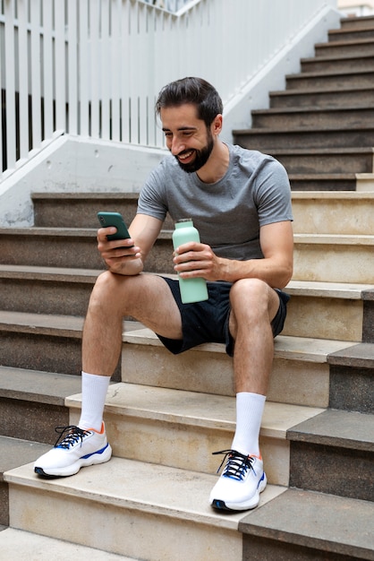 Homem sorridente de vista lateral segurando smartphone