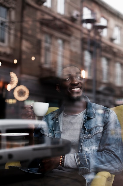 Homem sorridente, desfrutando de café dentro de casa