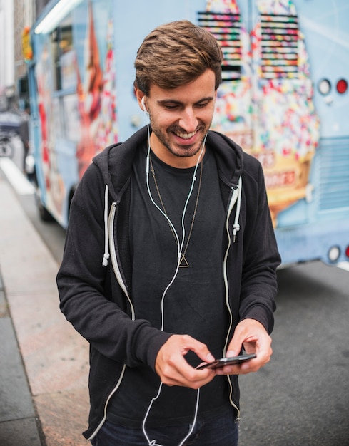 Foto grátis homem sorridente, digitando em um telefone