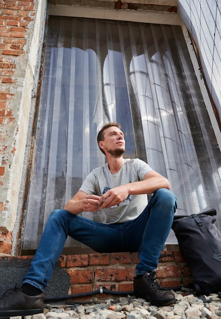 Homem sorridente está sentado nas escadas ao ar livre