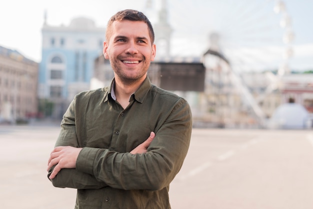 Homem sorridente, ficar, em, parque divertimento, com, braço cruzou