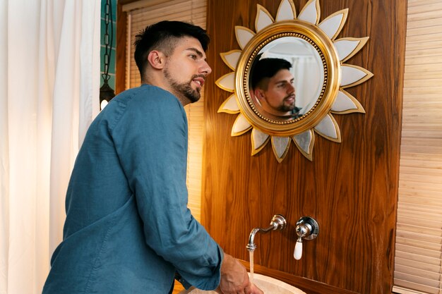 Foto grátis homem sorridente lavando as mãos vista lateral