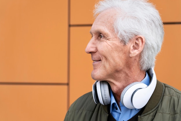 Homem sorridente mais velho na cidade com fones de ouvido