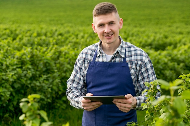 Homem sorridente na fazenda com tablet