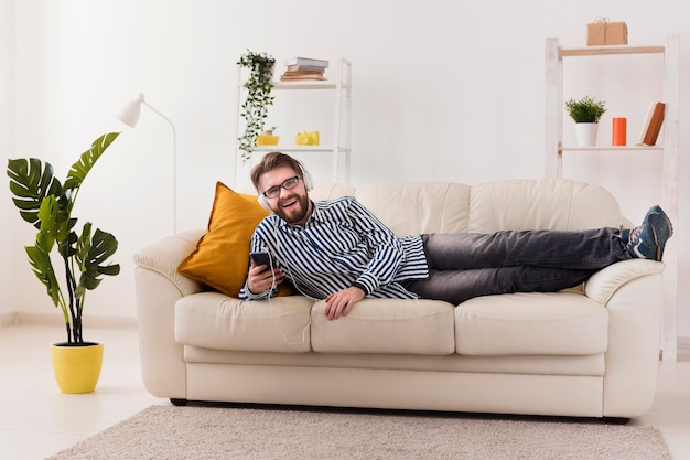 Homem sorridente no sofá a gostar de música