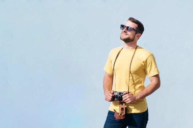 Homem sorridente, óculos sol cansados, segurando, câmera, e, olhando