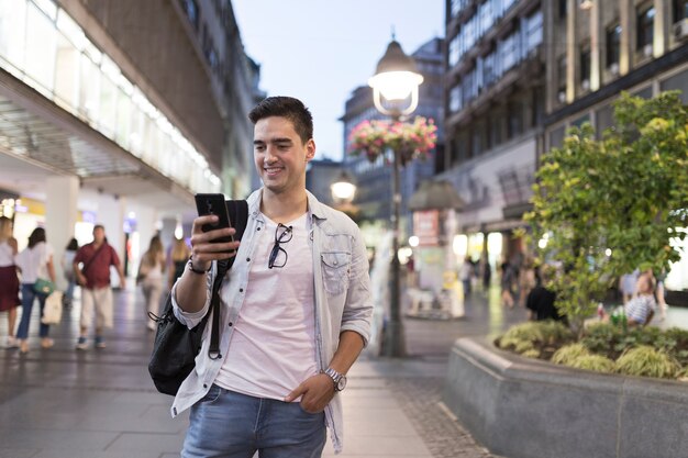 Homem sorridente, olhando para a tela do telefone móvel