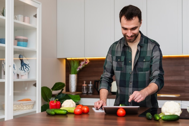 Foto grátis homem sorridente, olhando para tablet na cozinha