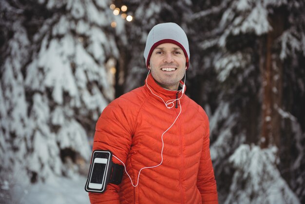 Homem sorridente ouvindo música em fones de ouvido no smartphone