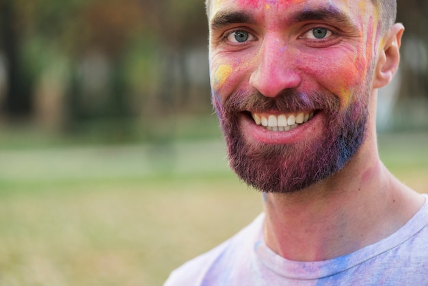 Homem sorridente posando com o rosto pintado no holi