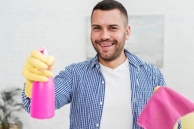 Homem sorridente posando com pano e produto de limpeza